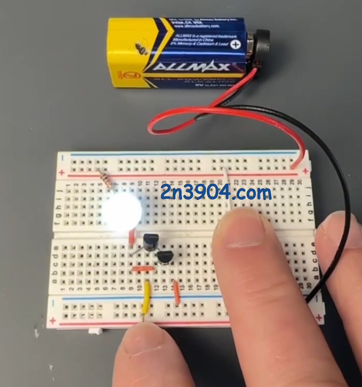 Finger touching the base of the first 2N3904 transistor, causing an LED to light using a Darlington pair and a 9 volt battery